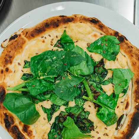 Rustic pizza with fresh spinach and golden crust, inviting and fragrant.