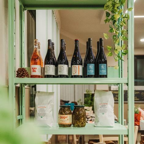 Colorful shelf with wines, artisanal foods, and plants, warm and welcoming atmosphere.