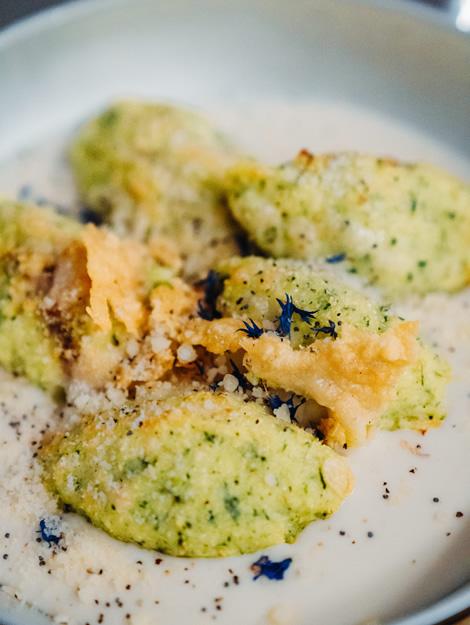 Creamy green gnocchi with cheese, pepper, and delicate blue flowers.
