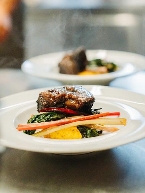 Gourmet dish: succulent meat, colorful vegetables, warm and inviting atmosphere.