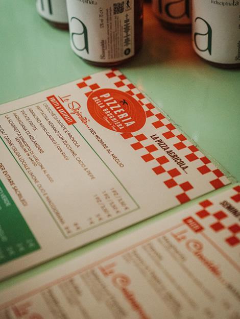 Rustic pizzeria menu on green table, warm and cozy atmosphere.