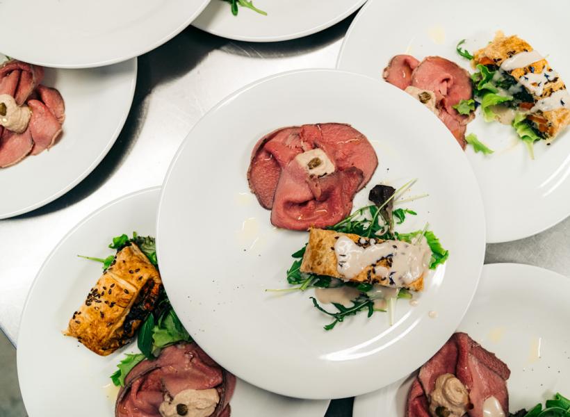 Elegant plates with succulent meat and creamy sauce on a bed of greens.