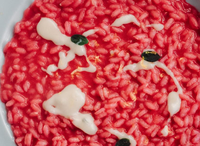 Vibrant red risotto with white cream and green leaves, an explosion of colors.