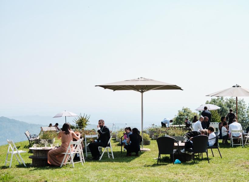 People relaxing outdoors, enjoying the sun among umbrellas and nature.