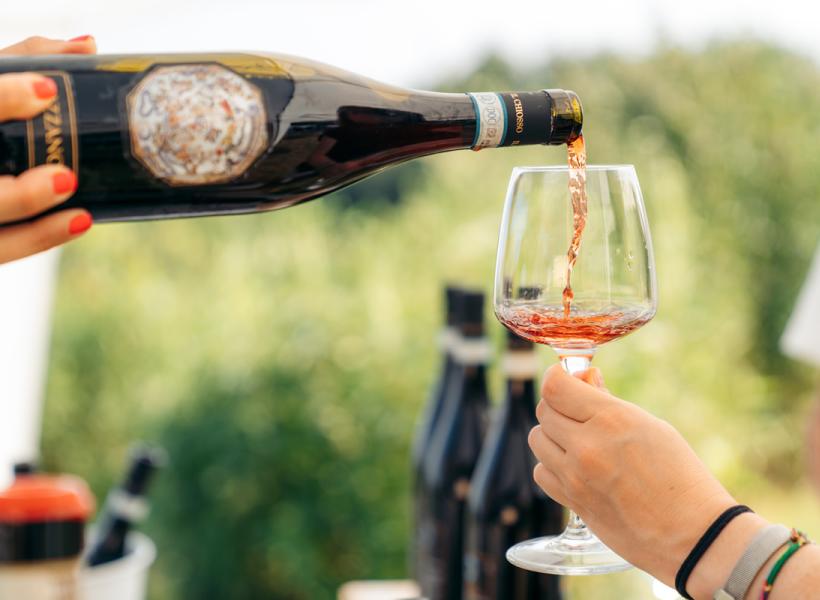 Red wine poured into glass, summer vibe, outdoor conviviality.