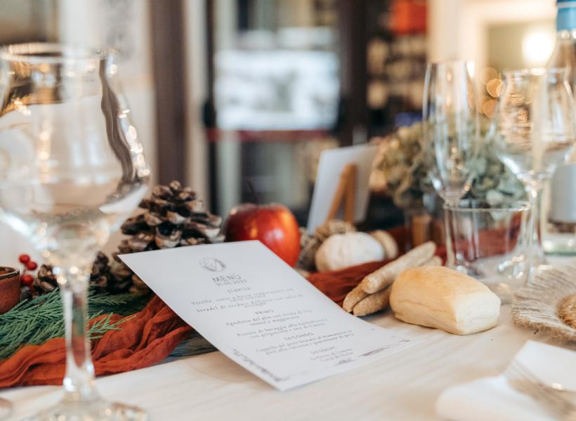 Elegant table with menu, glasses, bread, and autumn natural decorations.
