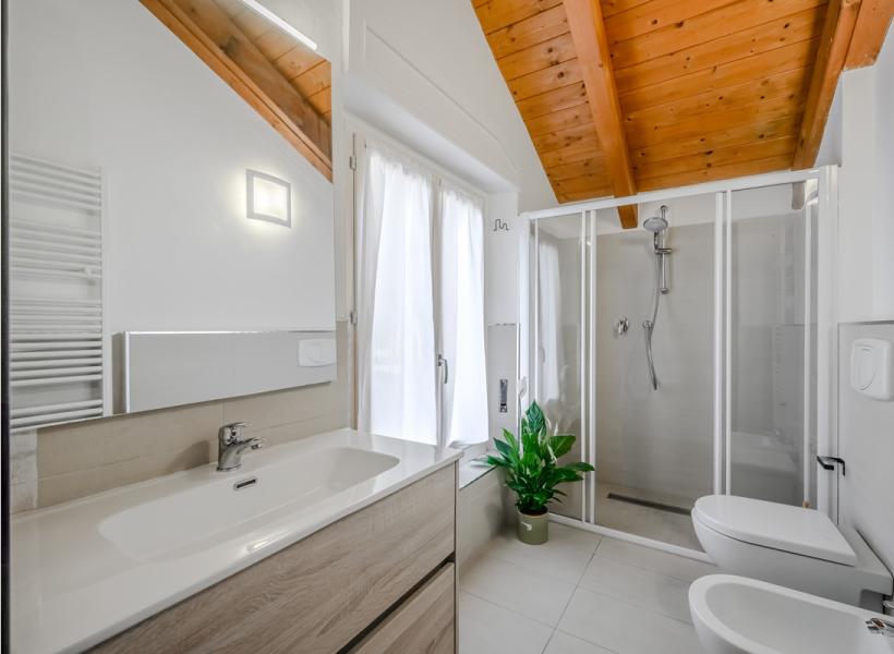 Modern, bright bathroom with wooden ceiling and green plant.