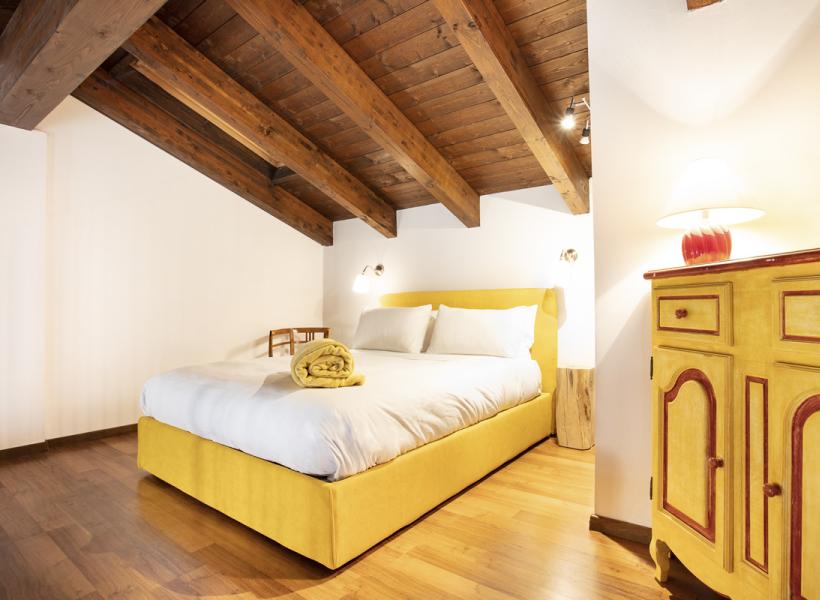 Cozy room with a yellow bed and warm wooden beams.