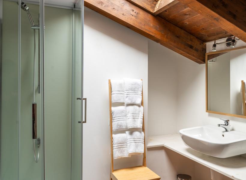 Cozy bathroom with modern shower and warm wooden ceiling.