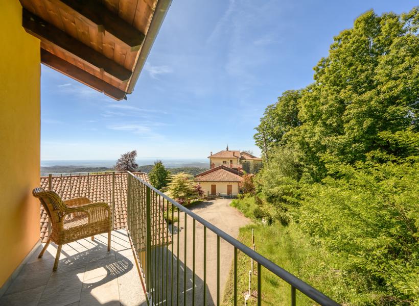 Sunny balcony with views of green hills and clear sky.